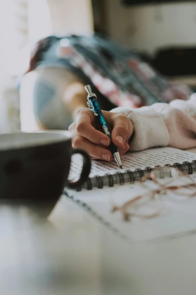 Donna che scrive su un quaderno in un momento di riflessione
