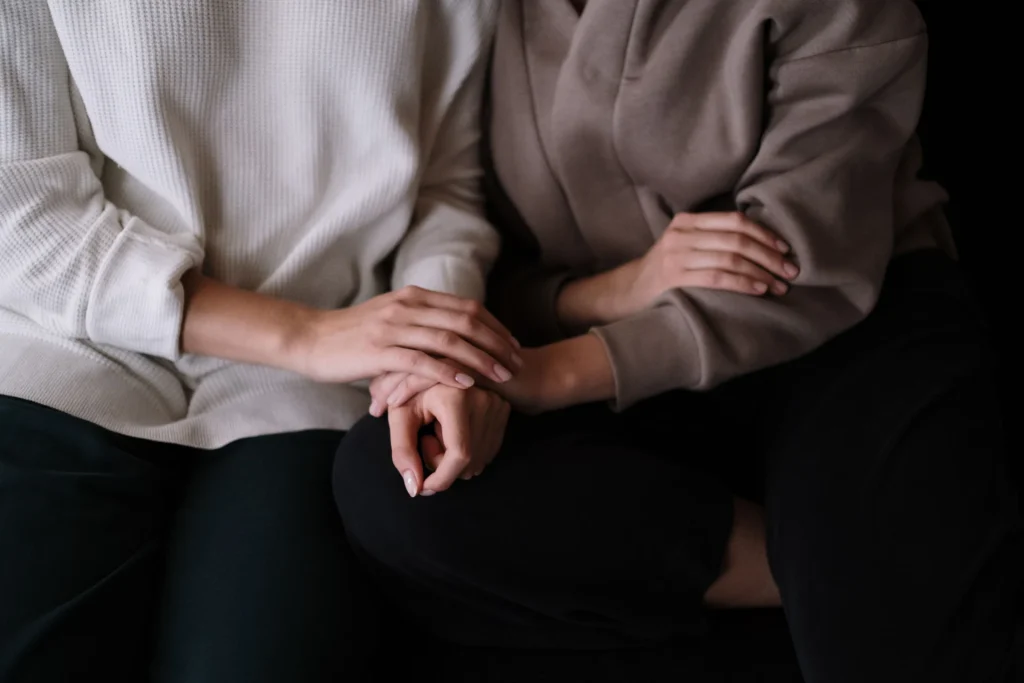 Le parole che non riusciamo a dire Due persone si tengono per mano in un gesto di conforto e sostegno