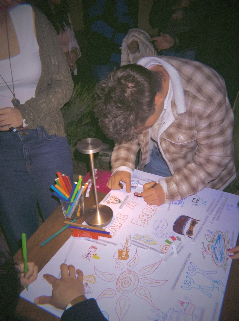 Un ragazzo disegna con i pennarelli su un cartellone di Take a Breath durante un aperitivo serale