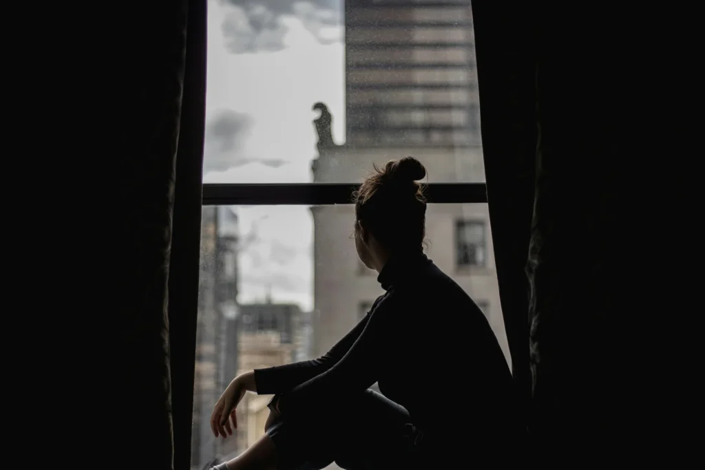 La noia e il tempo che non sappiamo abitare Persona seduta su una finestra in un momento di pausa e riflessione
