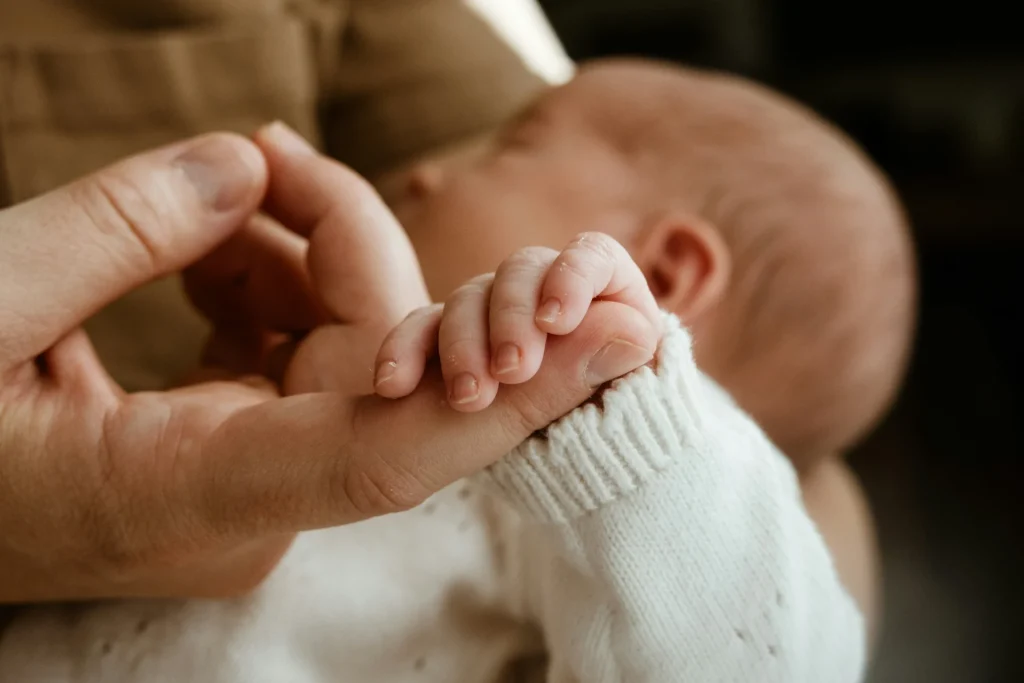 Mano di un adulto che tiene la mano di un neonato
