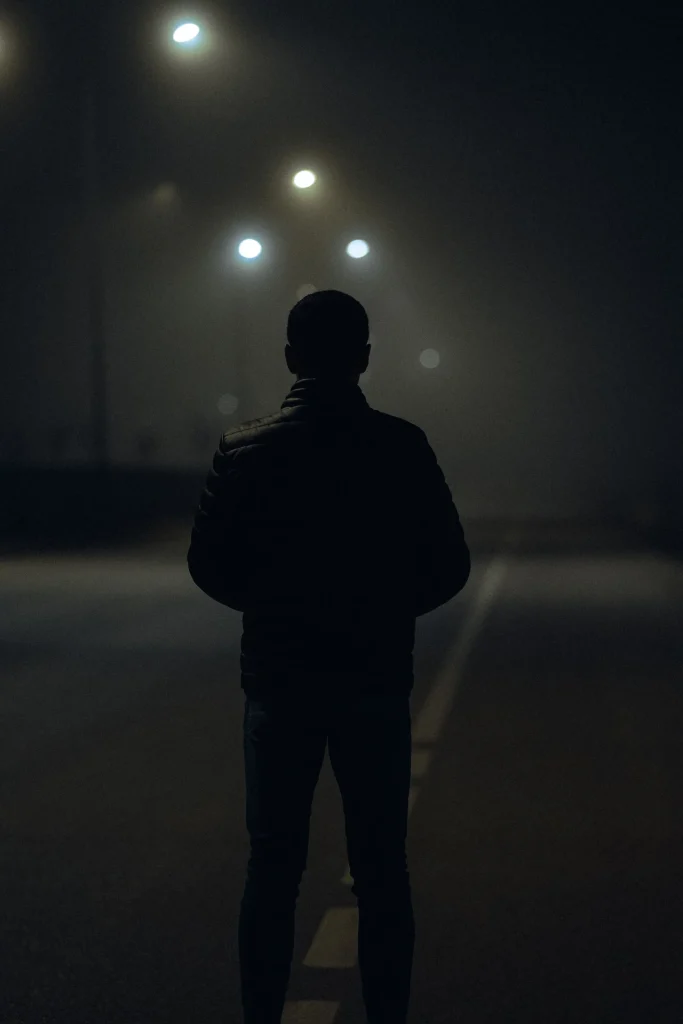 Sagoma di una persona sola sotto un lampione in una notte di nebbia