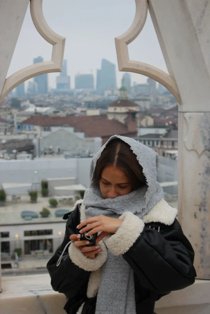 Una giovane donna guarda lo skyline di Milano dalle terrazze del Duomo