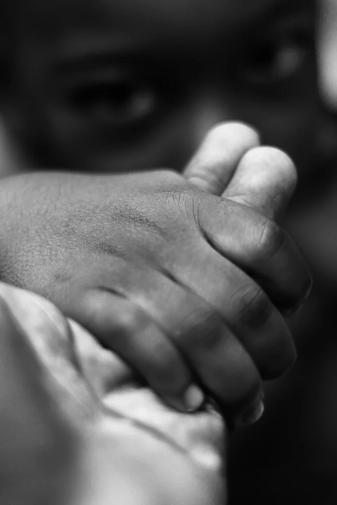 650 milioni di infanzie finite troppo presto Mano di una bambina stretta in quella di un adulto, in bianco e nero: il matrimonio precoce toglie alle ragazze il tempo di crescere