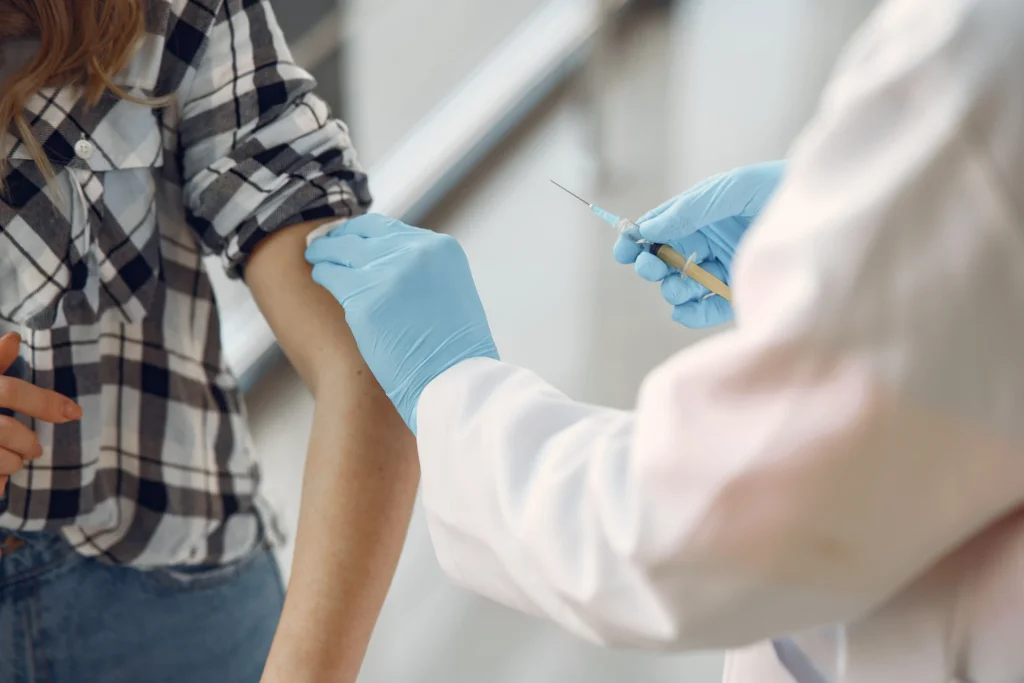Operatrice sanitaria somministra il vaccino antinfluenzale nel braccio di una paziente