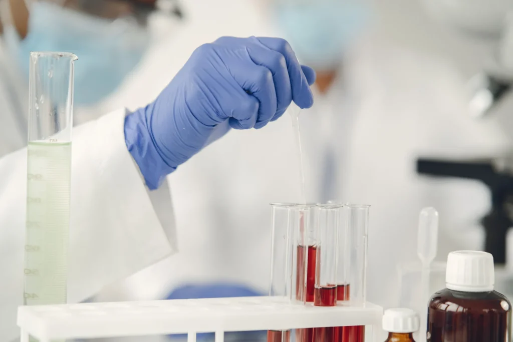 Mani con guanti protettivi usano una pipetta su una provetta in laboratorio