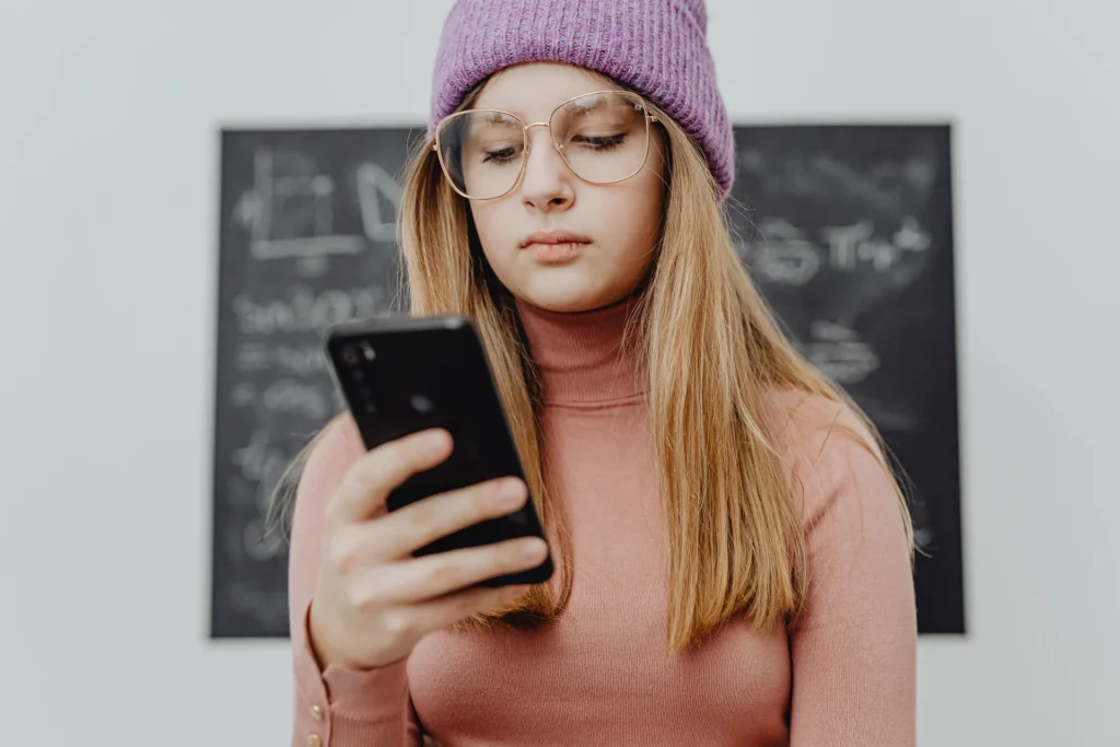 Una ragazza adolescente guarda lo smartphone in classe