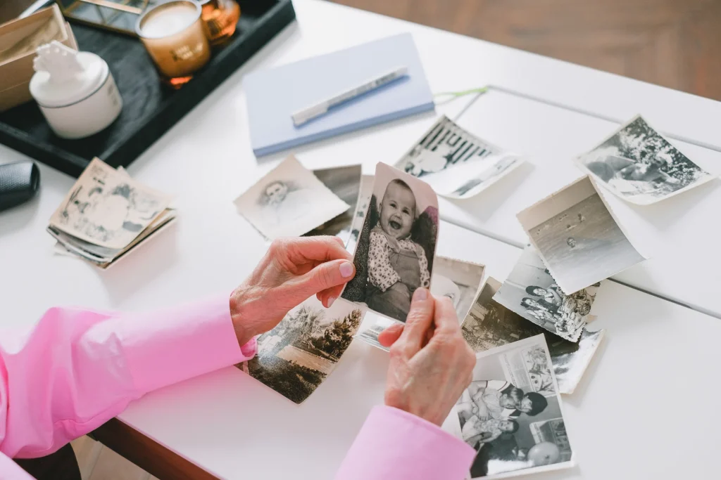 Alzheimer, il prezzo di vivere più a lungo Mani che sistemano vecchie fotografie di famiglia in bianco e nero su un tavolo